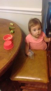 A 1-year old spreads hummus on the table.